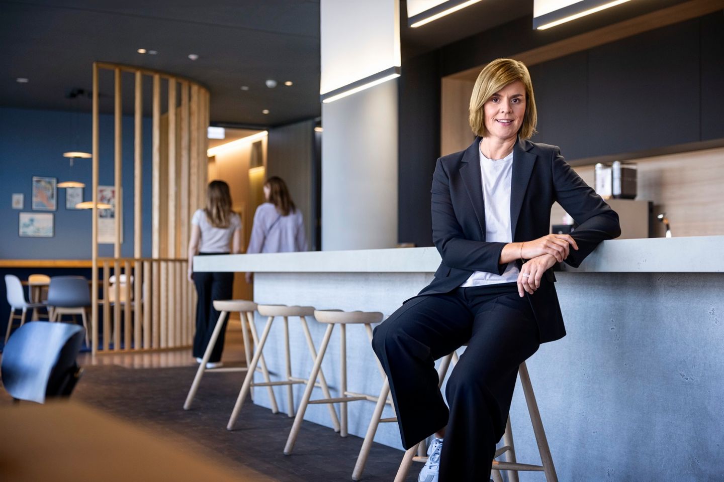 Dr. Eva Griewel, finansijska direktorica (CFO) grupe EOS, sedi u društvenom prostoru na visokom stolu, obučena u crni bleyzer.
