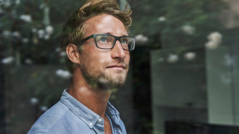 Mladi muškarac generacije Z zabrinuto gleda kroz prozor.