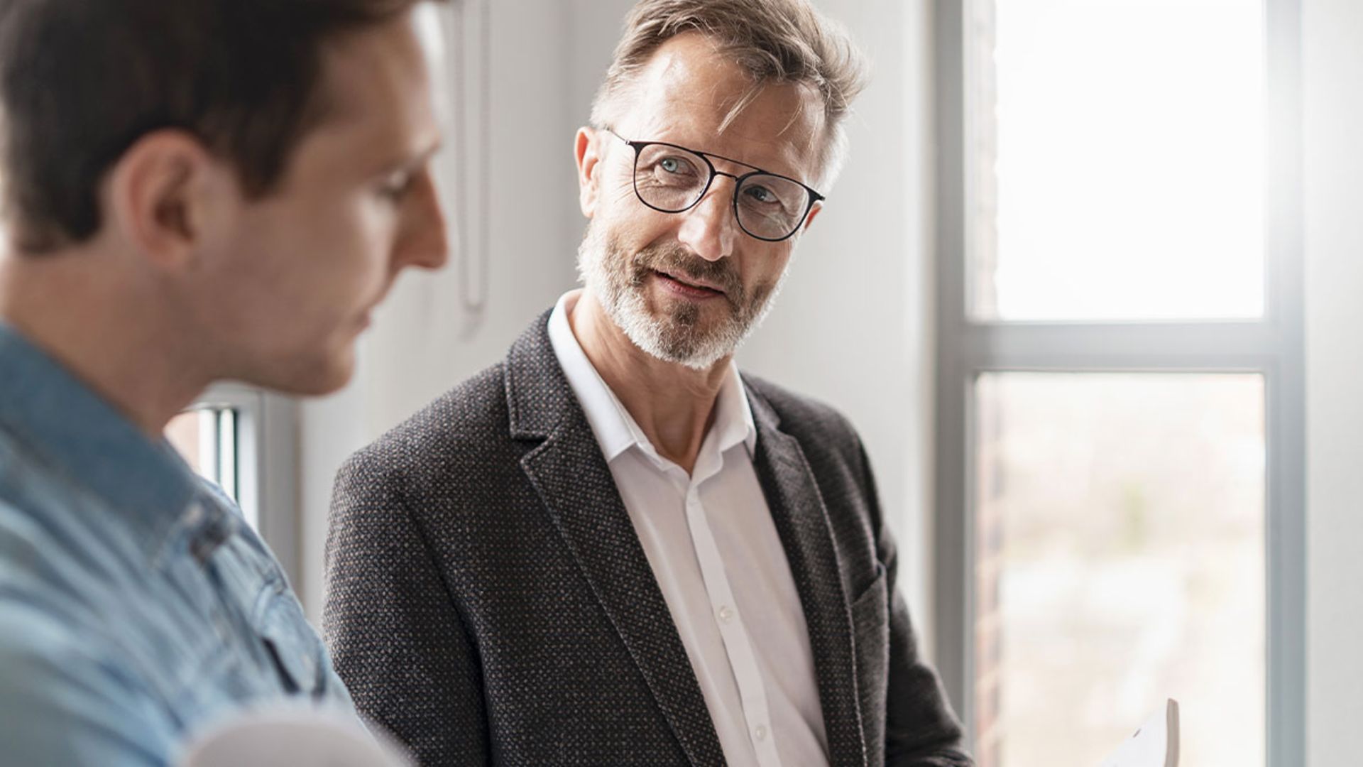 Dva muškarca u uredu raspravljaju o rezultatima studije "Evropske platne prakse 2025" EOS Grupe o digitalizaciji u upravljanju potraživanjima.