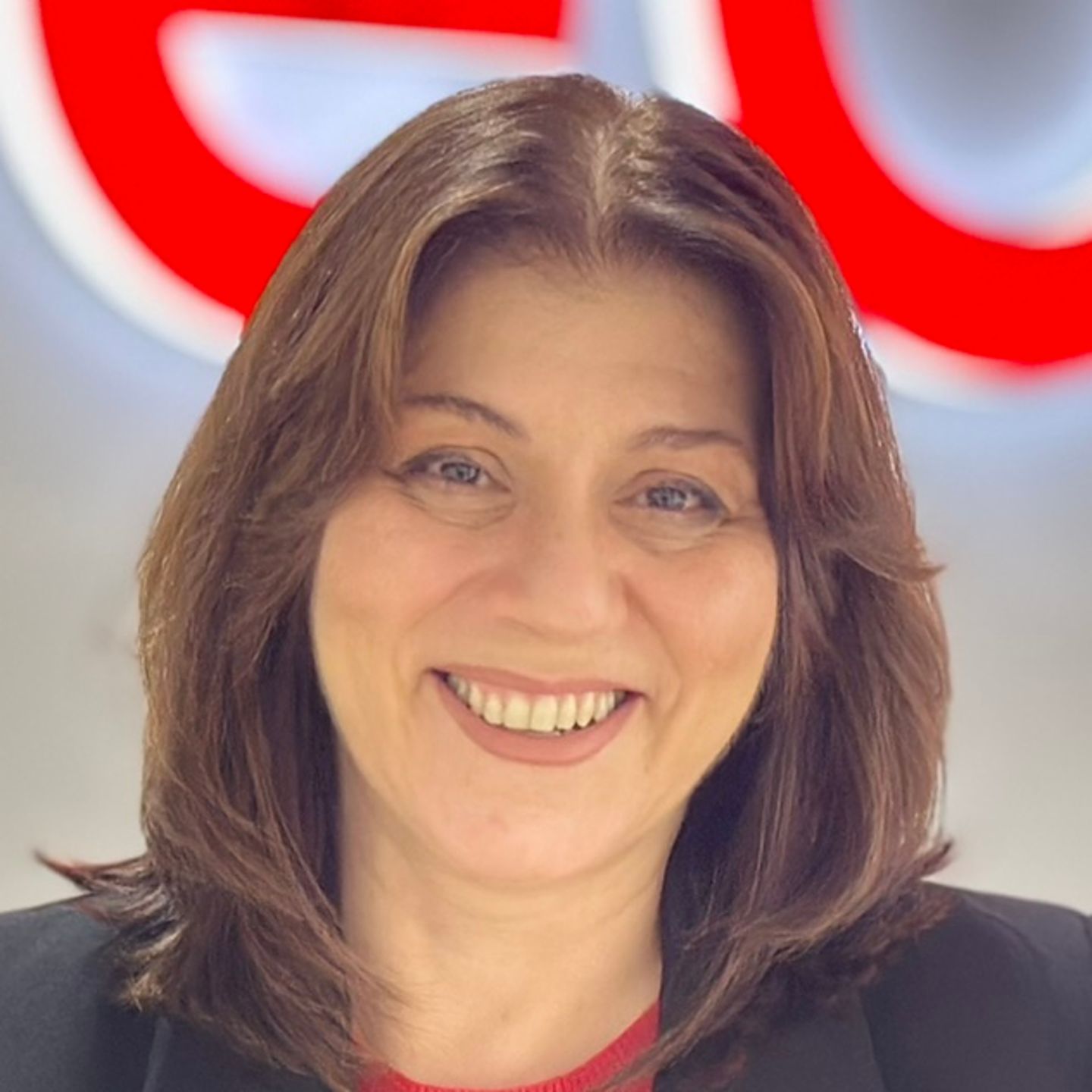Belén Barreiro, agentica kontakt centra u EOS-u u Španiji, naslonjena je na pult u crnom blejzeru ispred sjajnog EOS logotipa.