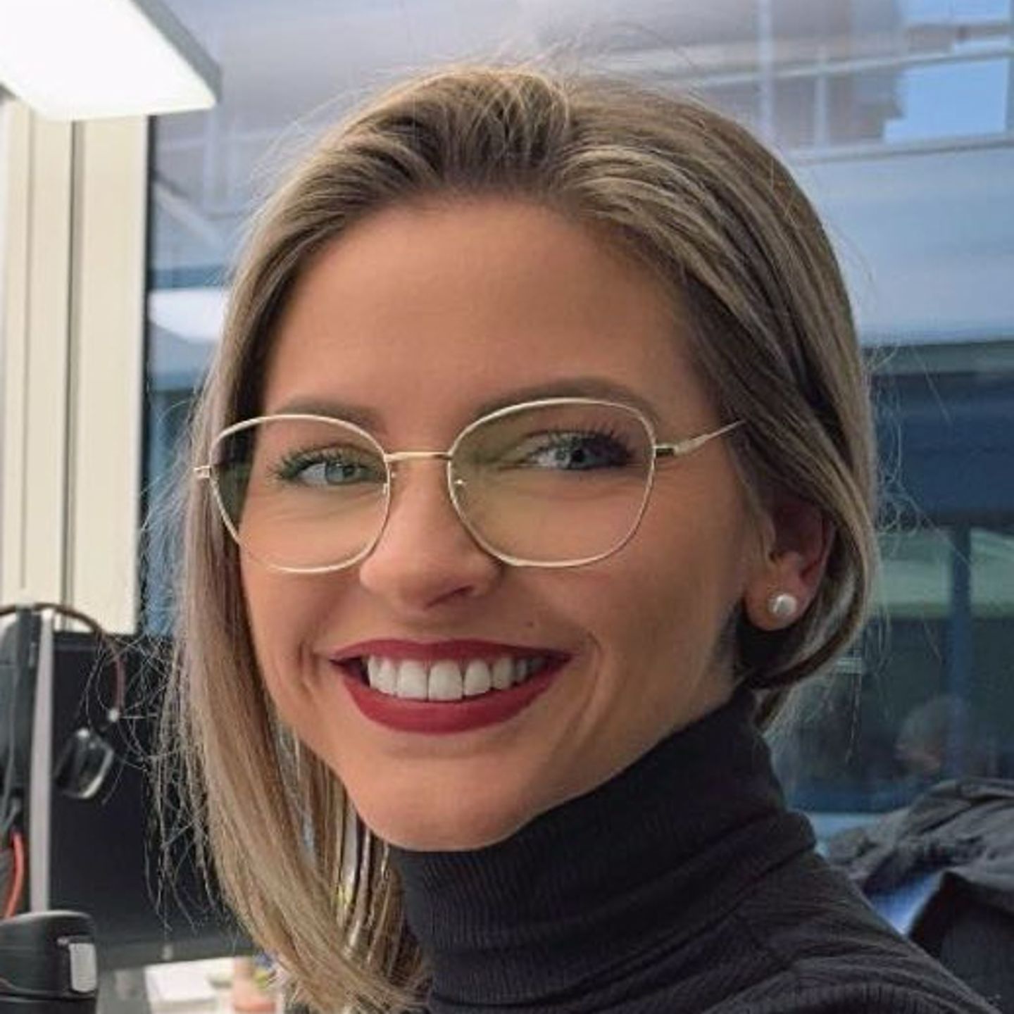 Genny Bollinger, stručnjak za restrukturiranje dugova u EOS-u u Švicarskoj, sjedi za svojim stolom u sivom džemperu s dolčevicom i smiješi se u kameru.