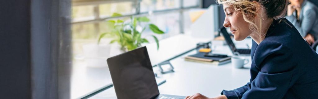 Mlada žena radi na laptopu u modernoj kancelariji.