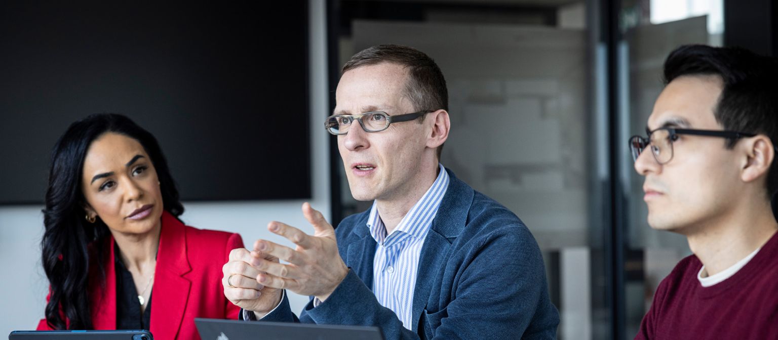 Tri osobe razgovaraju u kancelariji.