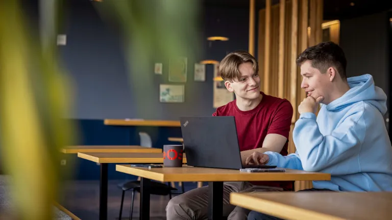 Dvoje zaposlenika sarađuje na laptopu, promovirajući partnerstvo i pravednost na radnom mjestu.